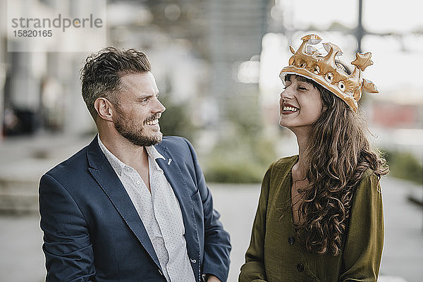 Lächelnder Geschäftsmann schaut eine Frau an  die eine Krone trägt
