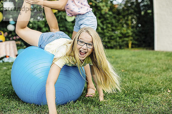 Porträt eines glücklichen Mädchens auf einem Sitzball im Garten