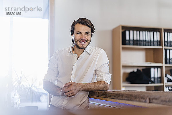Porträt eines lächelnden Geschäftsmannes im hölzernen Großraumbüro