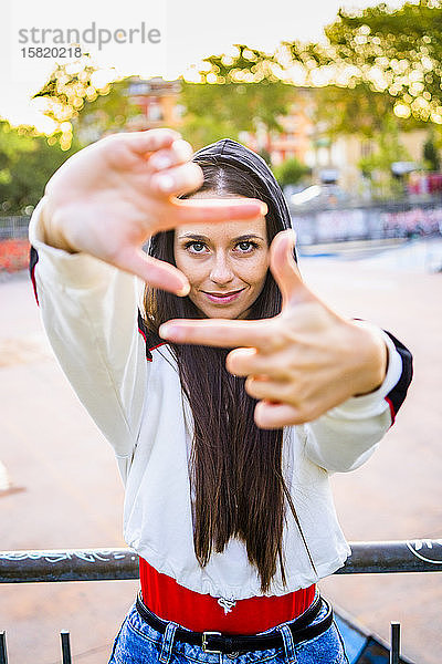 Junge Frau beim Rahmenformen mit dem Finger im Skatepark