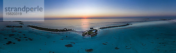 Malediven  Hubschrauberansicht der Bungalows des Touristenresorts  die sich bei Sonnenuntergang entlang der Küste der Insel Maadhoo erstrecken