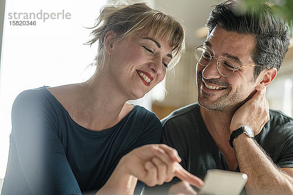 Glückliches Paar nutzt Smartphone zu Hause