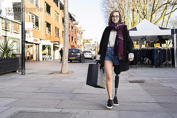 Porträt einer selbstbewussten jungen Frau mit Beinprothese beim Spaziergang in der Stadt