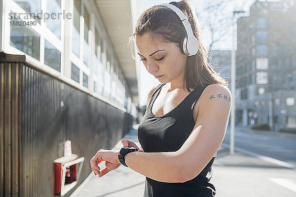 Sportliche junge Frau mit Smartwatch in der Stadt