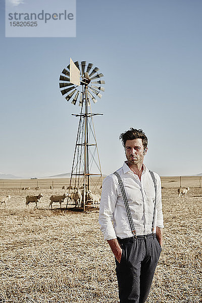 Mann in altmodischer Kleidung mit Schafherde auf dem Land