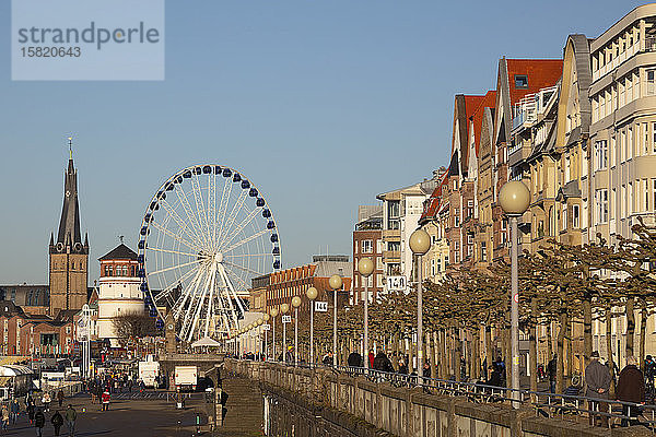 Deutschland  Nordrhein-Westfalen  Düsseldorf  Reihe von Straßenlaternen entlang der Uferpromenade mit dem Riesenrad und der St.-Lambertus-Kirche im Hintergrund