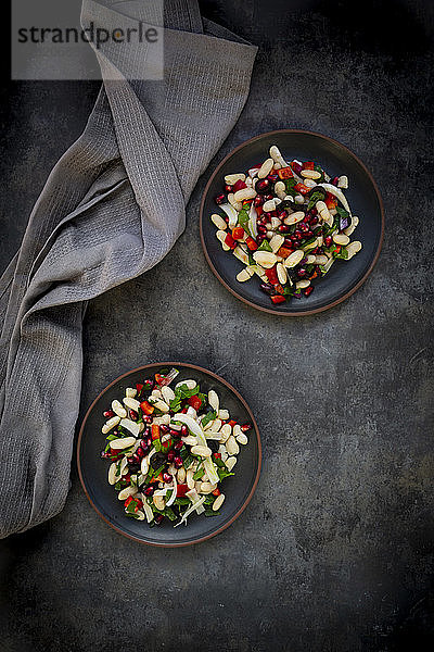 Zwei Teller Cannellini-Bohnensalat mit Fenchel  Paprika  schwarzen Oliven  Granatapfelkernen  Minze und Petersilie