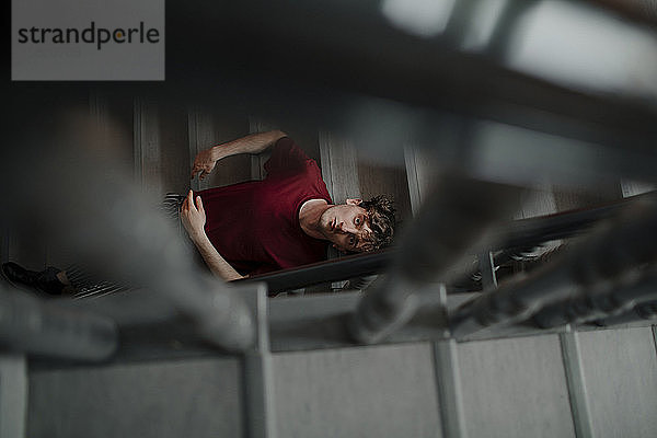 Porträt eines ernsthaften jungen Mannes  der auf einer Treppe sitzt und nach oben schaut