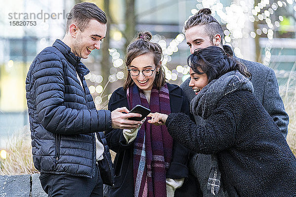 Glückliche Freunde schauen auf Smartphones in der Stadt