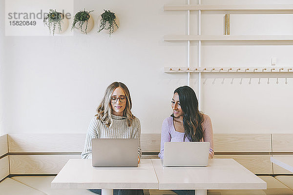 Zwei Frauen benutzen Laptops in einem Café