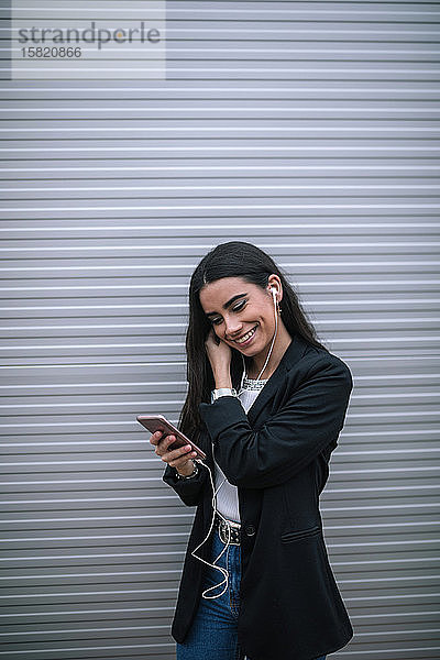 Porträt einer glücklichen jungen Frau mit einem Smartphone und Kopfhörern