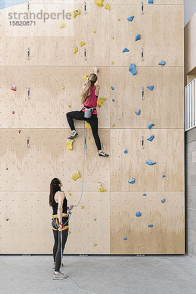 Frau mit einem Seilsicherungspartner an der Wand in der Kletterhalle