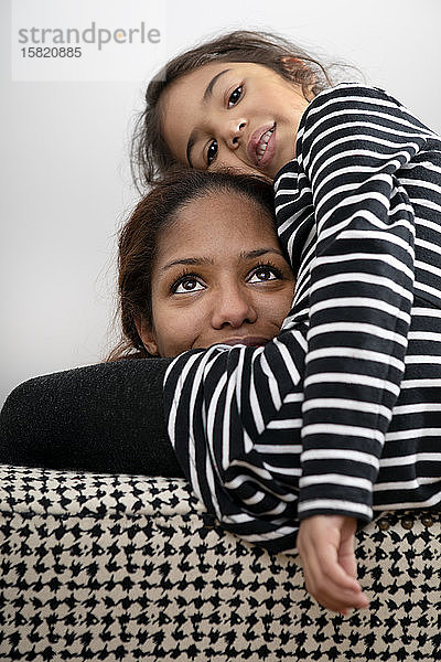 Porträt einer glücklichen Mutter  die mit ihrer kleinen Tochter kuschelt