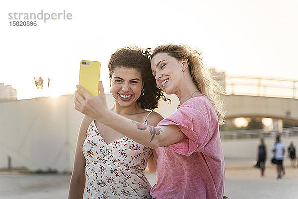 Glückliche Freunde  die bei Sonnenuntergang ein Selfie im Freien machen