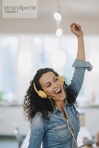 Glückliche Frau hört Musik  singt und tanzt  benutzt Smartphone und Kopfhörer