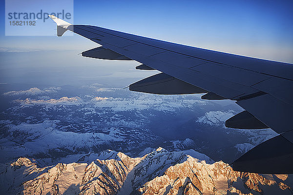 Frankreich  Auvergne-Rhône-Alpes  Tragfläche des Airbus A321 im Morgengrauen über den europäischen Alpen und dem Genfer See