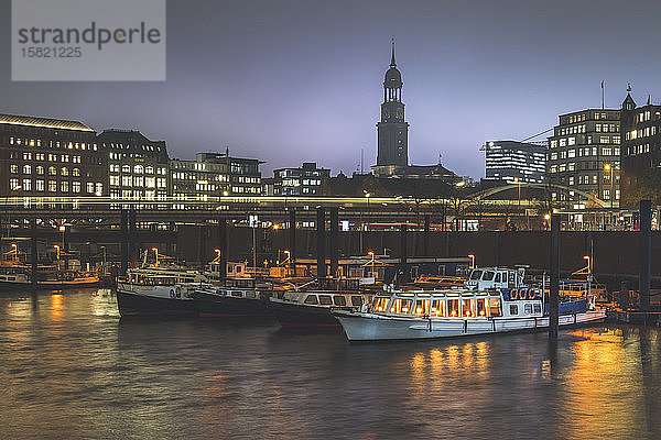 Deutschland  Hamburg  In der Abenddämmerung im Stadthafen festgemachte Boote mit Lichtspur und Turm der St. Michaels-Kirche im Hintergrund