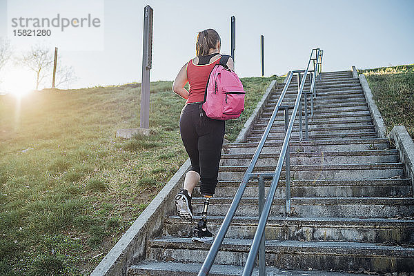 Sportliche junge Frau mit Beinprothese beim Treppensteigen