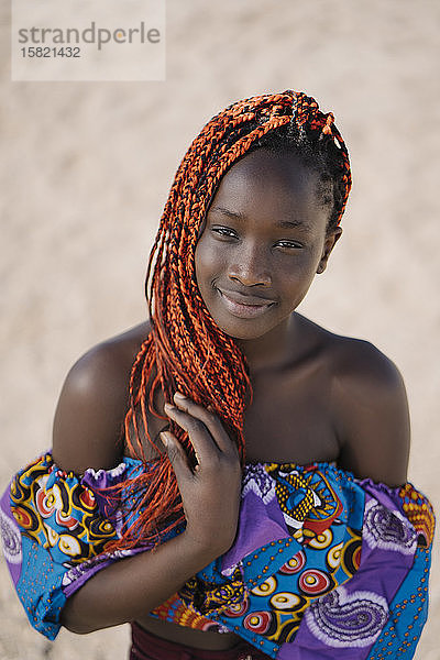 Porträt eines lächelnden Teenager-Mädchens mit Zöpfen im Freien