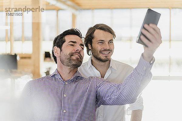 Zwei Geschäftsleute beim Selfie im hölzernen Großraumbüro