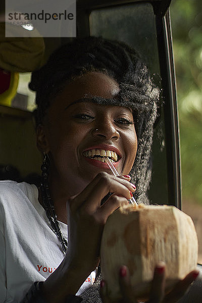 Porträt einer Frau  die im Auto Kokosnusswasser trinkt