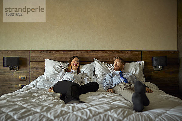 Geschäftsmann und Geschäftsfrau liegen auf dem Bett im Hotelzimmer