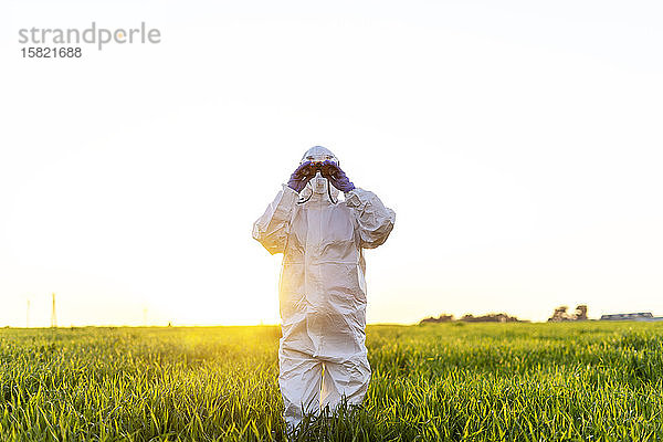 Wissenschaftlerin  die im Feld forscht und bei Sonnenuntergang durch ein Fernglas schaut