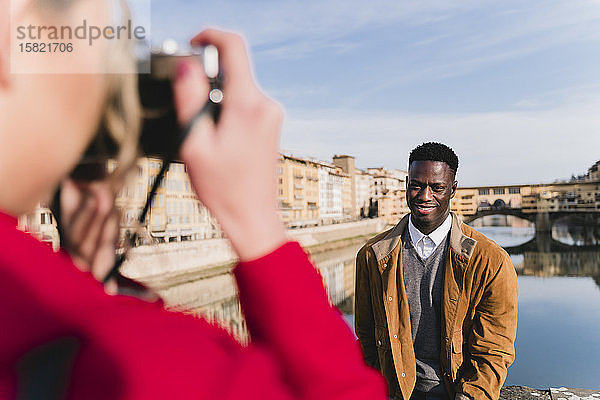 Junge Frau beim Fotografieren ihres Freundes auf einer Brücke über den Arno  Florenz  Italien