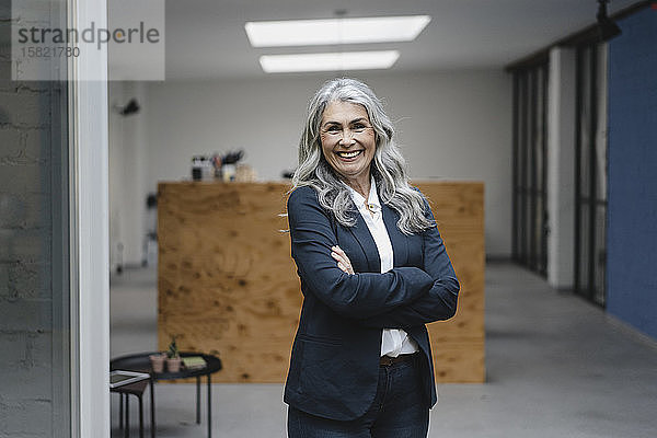 Porträt einer lächelnden  grauhaarigen Geschäftsfrau in einem Loft-Büro