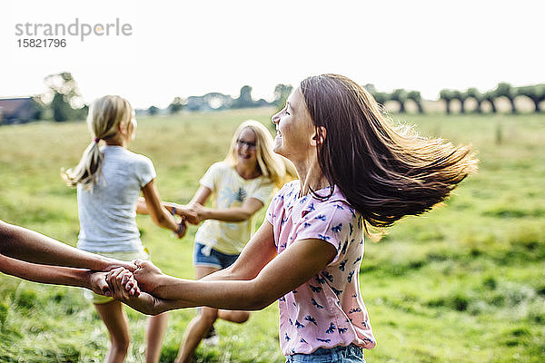 Glückliche Mädchen tanzen gemeinsam auf einem Feld