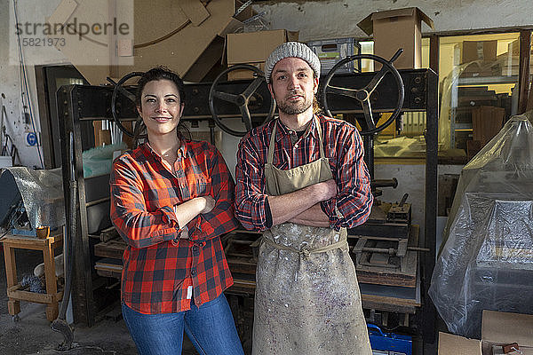 Porträt einer selbstbewussten Handwerkerin und eines Handwerkers in ihrer Werkstatt