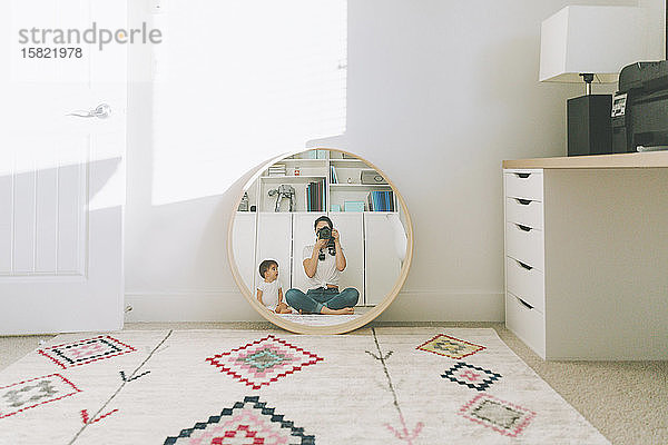 Spiegelung einer Mutter  die sich und ihr Baby im Spiegel fotografiert