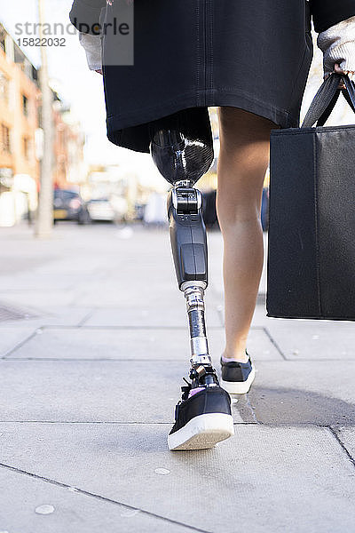 Niedriger Anteil einer Frau mit Beinprothese beim Gehen in der Stadt