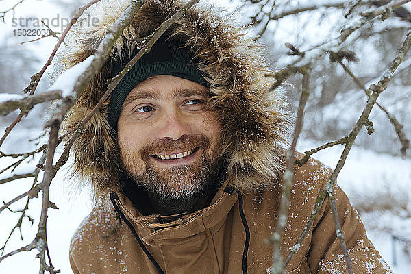 Porträt eines lächelnden Mannes mit Kapuzenjacke im Winter