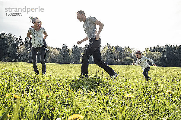 Familie mit zwei Kindern amüsiert sich im Frühling gemeinsam auf einer Wiese
