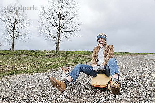 Porträt einer schreienden reifen Frau auf einem Bobbycar