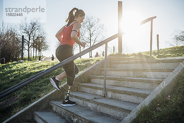Sportliche junge Frau mit Beinprothese beim Treppensteigen