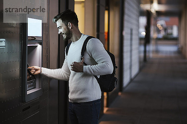 Mann  der Geld an einem Geldautomaten in der Stadt abhebt