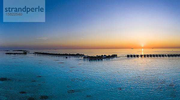 Malediven  Hubschrauberansicht der Bungalows des Touristenresorts  die sich bei Sonnenuntergang entlang der Küste der Insel Maadhoo erstrecken
