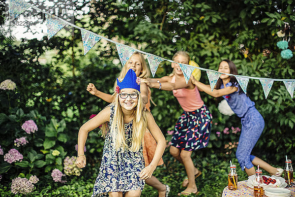 Glückliche Mädchen machen eine Conga-Linie auf einer Geburtstagsparty im Freien