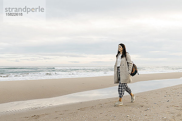 Junge Frau geht bei Sonnenuntergang an einem abgelegenen Strand spazieren