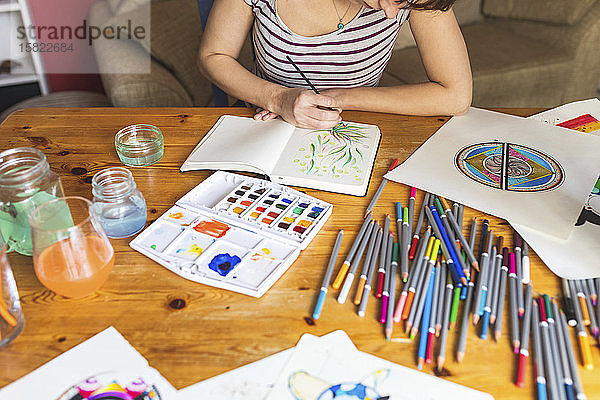 Schrägansicht einer Frau  die mit Aquarellfarben malt