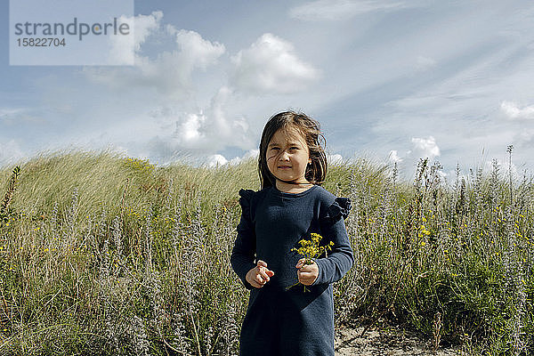 Porträt eines kleinen Mädchens mit gepflückten Blumen in den Dünen  Den Haag  Niederlande