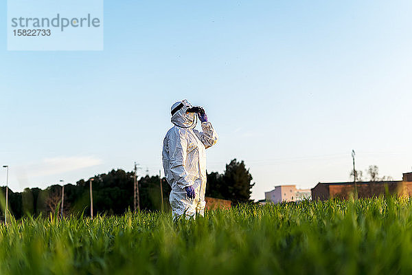 Wissenschaftlerin  die im Feld forscht und bei Sonnenuntergang durch ein Fernglas schaut