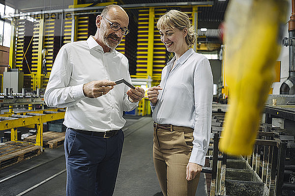 Mann und Frau untersuchen Werkstück in der Fabrik