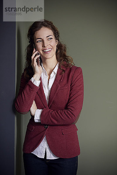 Porträt einer lächelnden Geschäftsfrau am Telefon im Büro