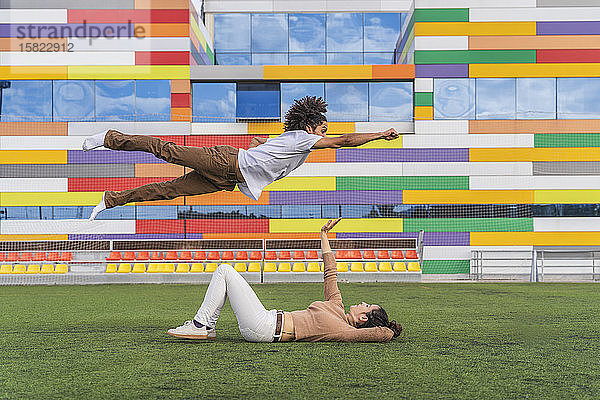 Tänzerin springt im Superhelden-Stil über den Partner und liegt auf Gras