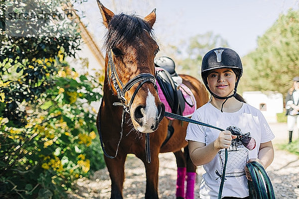 Teenager mit Down-Syndrom kümmert sich um Pferd und bereitet Pferd zum Reiten vor