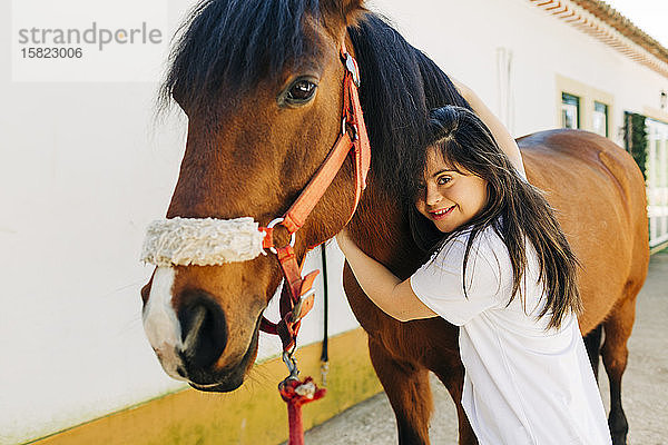 Teenager mit Down-Syndrom kümmert sich um Pferd und bereitet Pferd zum Reiten vor