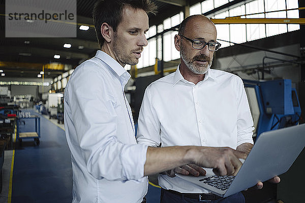 Zwei Männer mit Laptop in einer Fabrik